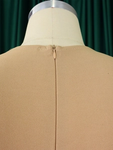 Detail of hidden zipper closure on the back of beige V-neck pencil dress with high waist
