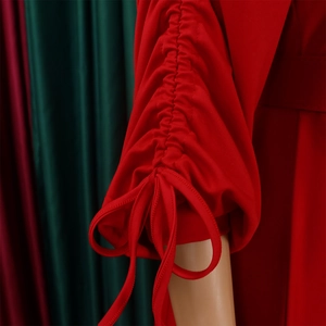Détail des manches plissées rouges avec rubans à nouer et texture de tissu en maille