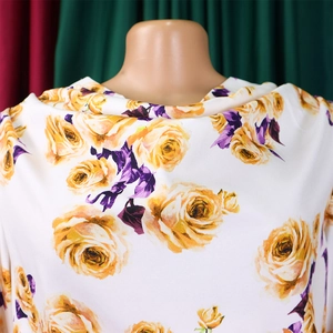 Détail du haut blanc avec imprimé roses jaunes et texture de feuilles violettes
