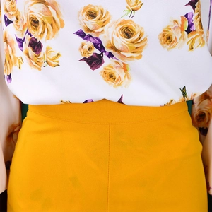 Détail du haut imprimé fleuri rentré dans un pantalon large jaune à taille haute