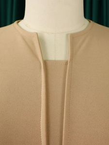 Close-up of the elegant V-neckline with layered faux two-piece detail on a khaki dress