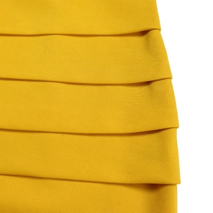 Close-up of mustard yellow V-neck dress featuring elegant layered pleats and textured fabric