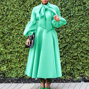 Detail of mint green dress featuring a bow neckline and lantern sleeves with a flared hem