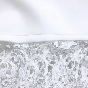 Detail of white evening dress featuring intricate floral lace stitching and fabric texture