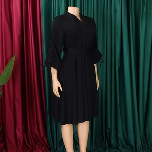 Détail d'une robe trapèze noire à manches longues avec manches plissées et ceinture assortie