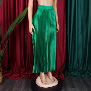 Détail d'une jupe longue plissée vert émeraude à taille haute avec aspect satiné
