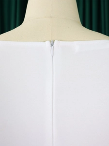 Détail d'une robe blanche avec fermeture éclair invisible et tissu texturé épais