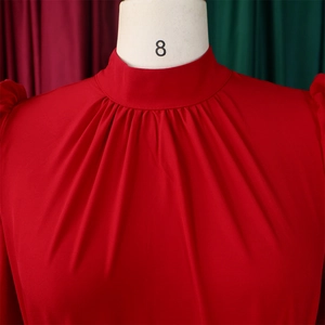 Detail of red mock neck blouse featuring elegant pleated collar and puff sleeve texture