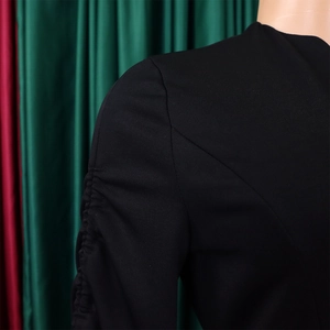 Détails d'une robe noire élégante montrant des manches froncées et des coutures d'épaule