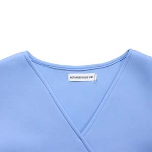 Close-up of a light blue V-neck dress collar featuring neat stitching and a white woven label