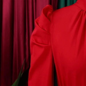 Detailed view of red puff sleeves with elegant pleated texture on a satin blouse