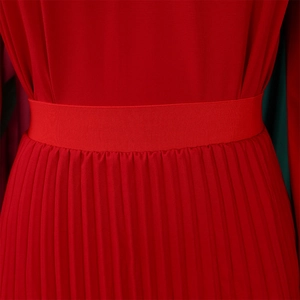 Detail shot of the red high-waisted elastic band and fine pleated texture of the skirt