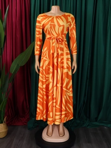 Detail of tropical floral print on a long-sleeved dress with waist tie and round neck