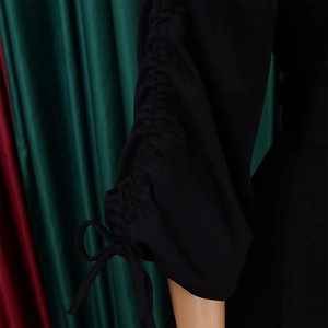 Détail de la manchette d'une robe noire à manches longues avec ruchage et nœud décoratif
