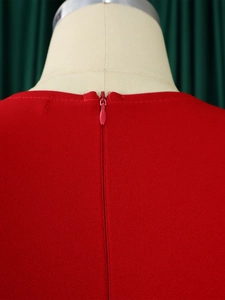 Close-up detail of the concealed back zipper and stitching on the red V-neck pencil dress