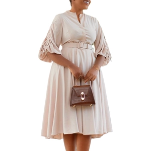 Détail des manches bouffantes plissées beiges et de la ceinture assortie sur la robe