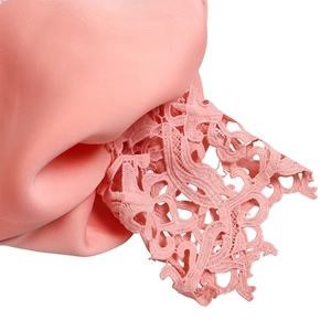 Detailed macro view of delicate pink floral lace embroidery on soft evening gown fabric