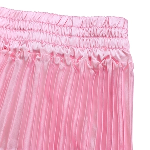 Détail d'une jupe plissée rose montrant la taille élastique et le tissu satiné lisse