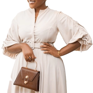 Détail d'une robe beige clair à col en V avec manches bouffantes et sac à main marron