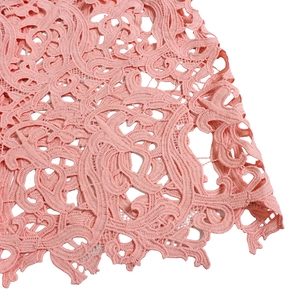 Close-up of pink lace dress fabric featuring intricate hollow floral embroidery details