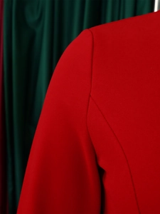 Detail shot of neat stitching on the shoulder and sleeve of a red V-neck pencil dress