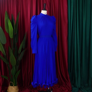 Macro detail of royal blue puff sleeve top with fine pleated skirt and ruffle hem