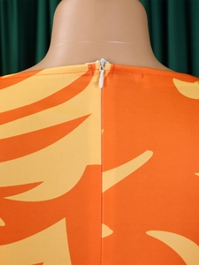 Detail view of high-quality invisible back zipper on orange abstract print midi dress