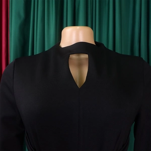 Detail of black long-sleeve dress featuring a teardrop cutout neckline and pleated texture