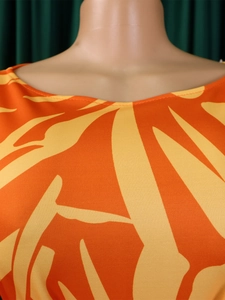 Detailed close-up of orange and yellow abstract print fabric on a stylish dress neckline
