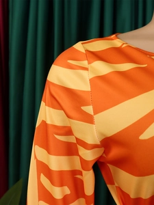 Detailed close-up of orange and yellow tiger print fabric on a stylish dress shoulder