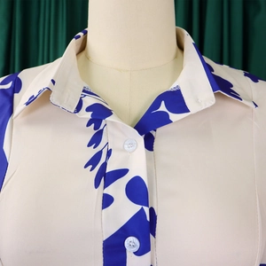 Close-up detail of shirt lapel collar with tropical leaf print and button closure
