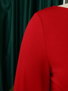 Détail de la robe rouge ajustée au tissu texturé sur mannequin avec fond vert élégant