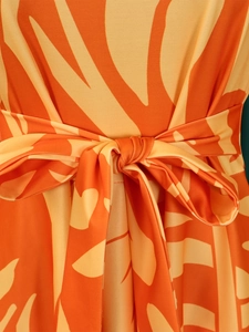 Detail of waist tie bow with abstract orange and yellow floral print on knit fabric