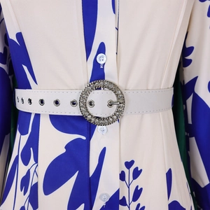 Close-up of printed dress waist with adjustable belt and rhinestone-studded buckle