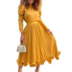 Detail of ginger yellow pleated dress with puff sleeves and ruffled hem on white background