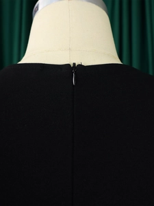 Close-up of invisible back zipper on black V-neck pencil dress with high waist design
