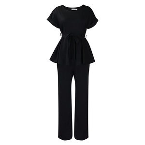 Détail de l'ensemble noir deux pièces avec haut à basque noué à la taille et pantalon droit