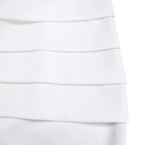 Detailed close-up of multi-layer bandage fabric with precise stitching on white dress