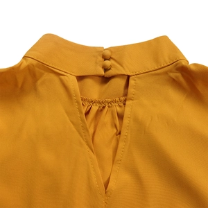 Detail view of yellow stand collar top with back keyhole opening and pleated neck detail