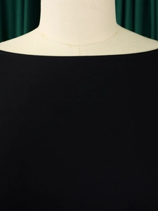 Détail de l'encolure bateau élégante et du tissu noir de qualité sur un mannequin de couture