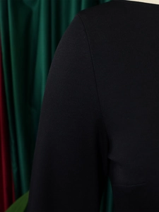 Détail de la robe en tricot noir montrant la texture du tissu et l'épaule de la manche