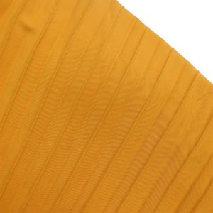 Detailed macro shot of mustard yellow pleated chiffon fabric with vertical texture