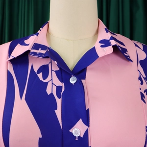 Detail shot of a pink floral dress featuring a classic collar and pearlescent buttons