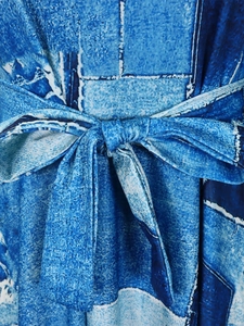 Detailed close-up of blue abstract print dress featuring a waist tie and fabric texture