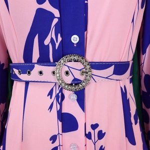 Detail of floral dress showing pink fabric with blue prints and a rhinestone belt buckle