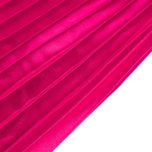 Détail macro d'une jupe longue plissée taille haute en satin brillant rose