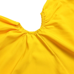 Detailed view of elastic smocked waist on a vibrant bright yellow one-shoulder dress