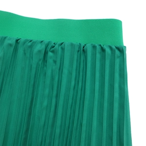 Detail of emerald green pleated skirt showing high elastic waistband and ribbed texture