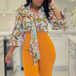 Detail of colorful leaf print shirt with V-neck tie and orange high-waist trousers