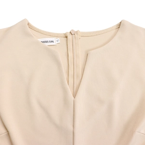 Close-up of V-neckline detail with invisible zipper and brand label on apricot dress